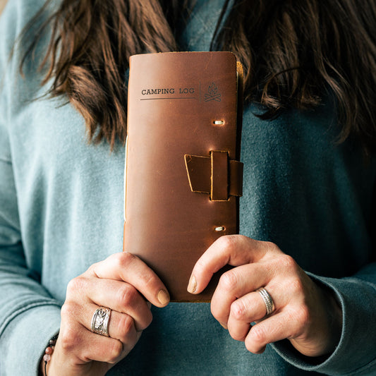 Person holding a leather camper journal to show the detail of the front cover